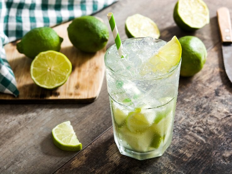 Ein Glas gefüllt mit selbst gemachtem Caipirinha - daneben die passenden Zutaten.