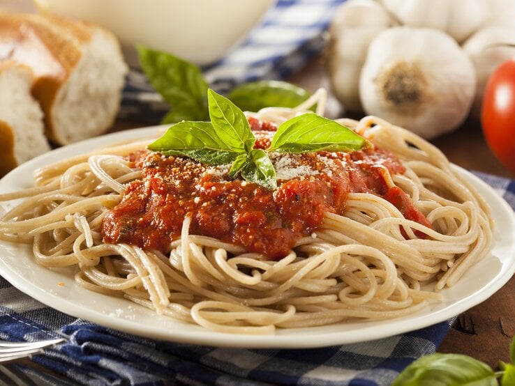 Ein weißer Teller, darauf eine Portion Spaghetti mit Tomatensoße. 