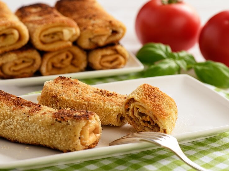 Panierte gerollte Pfannkuchen auf rechteckigem Teller. 