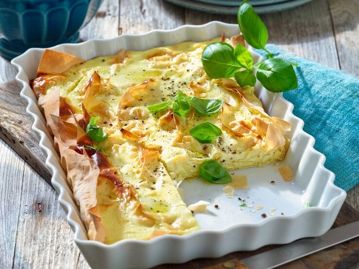 Ziegenkäse-Pie in einer viereckigen Auflaufform / Filoteig / frische Basilikumblätter / Untergrund Holz / 