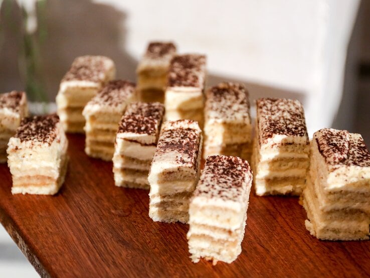 Cremiger, geschichteter Kuchen auf Holzbrett.  | © GettyImages/JunzPortraits