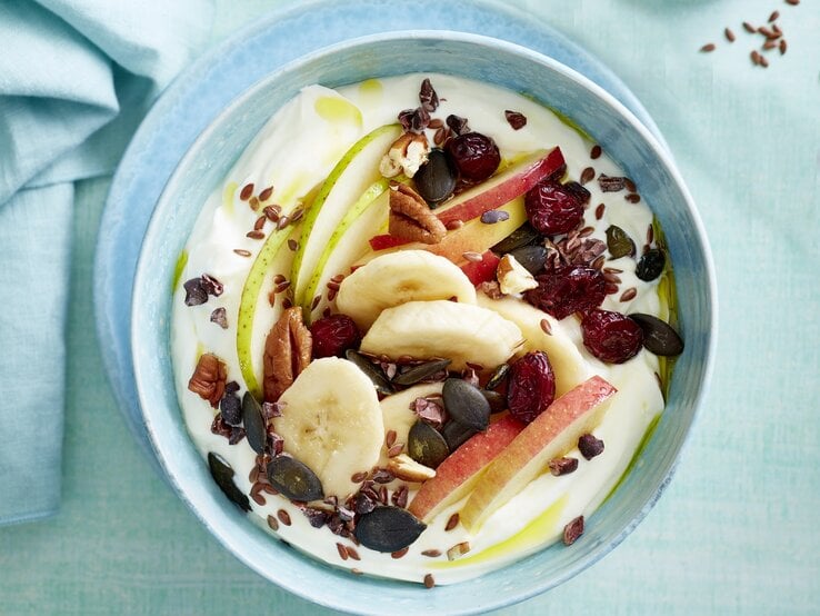 Quarkspeise mit Früchten in einer blauen Schüssel auf blauem Hintergrund.