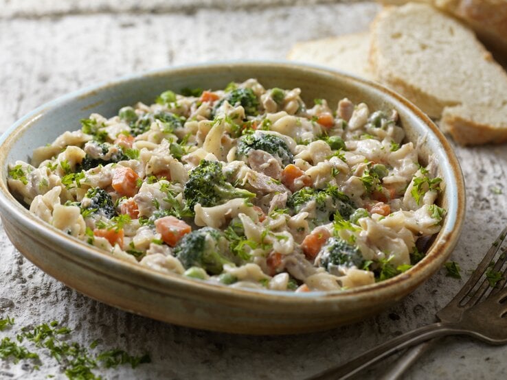 Leckere Nudelpfanne mit Thunfisch und Gemüse in Schale in rustikalem Ambiente.