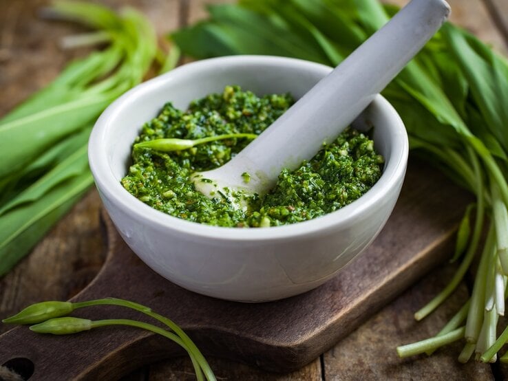 Weißer Mörser gefüllt mit hausgemachtem Bärlauchpesto.  | © iStock/ Anna_Shepulova