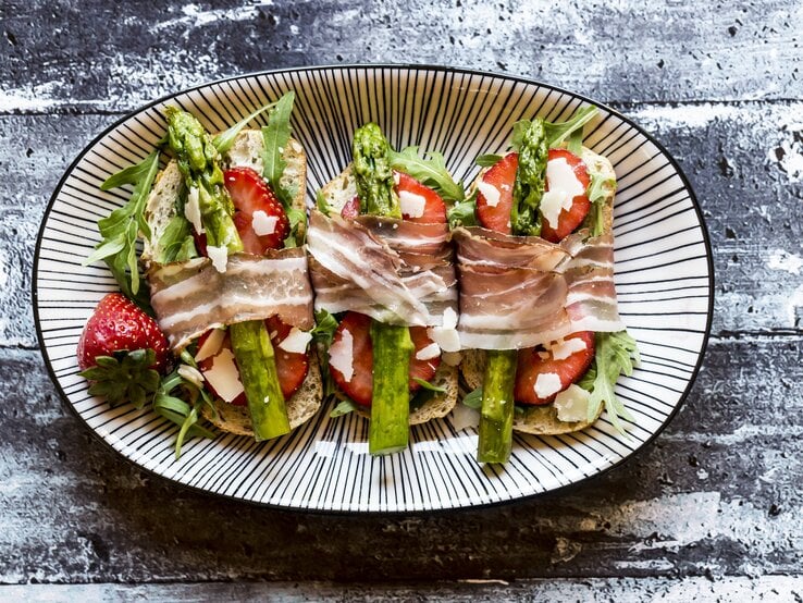 Bruschetta belegt mit Spargel, Erdbeeren, Rucola, Parmaschinken und Parmesan. | © Getty Images/ Westend61