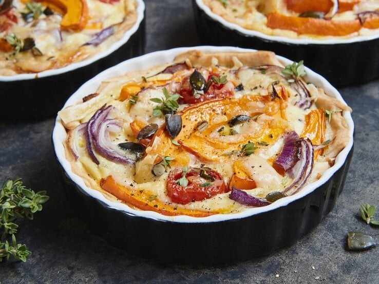 Die Kürbis-Quiche mit roten Zwiebeln in einer schwarzen Auflaufform gebacken. | © StockFood / Sporrer, Brigitte