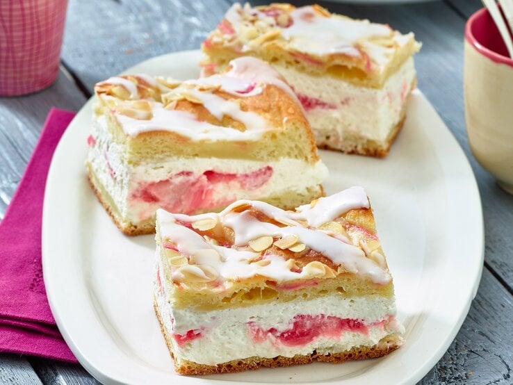 Auf einem ovalen hellen Teller aus Porzellan sind drei Stücke Rhabarber-Kuchen | © Matthias Liebich