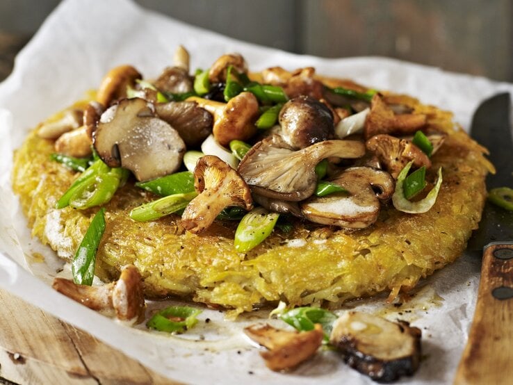 Ein Kartoffelrösti mit gemischten Pilzen auf Papier