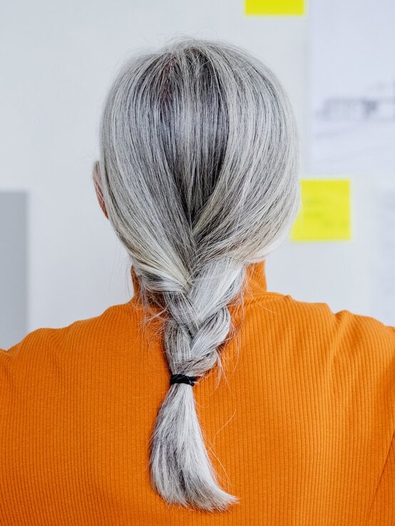 Frau mit grauen Haaren und einem geflochtenen Zopf | © Halfpoint/Getty Images