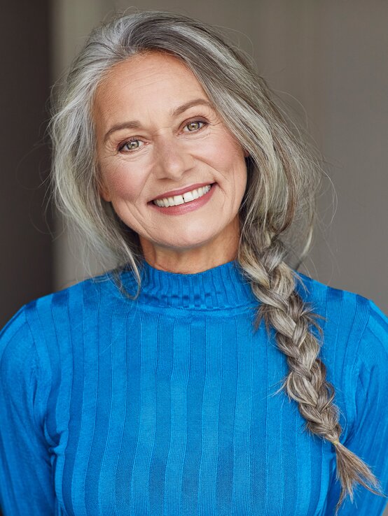 Frau mit langen, grauen Haaren trägt einen geflochtenen Zopf im Messy-Look. | © Getty Images/Westend61