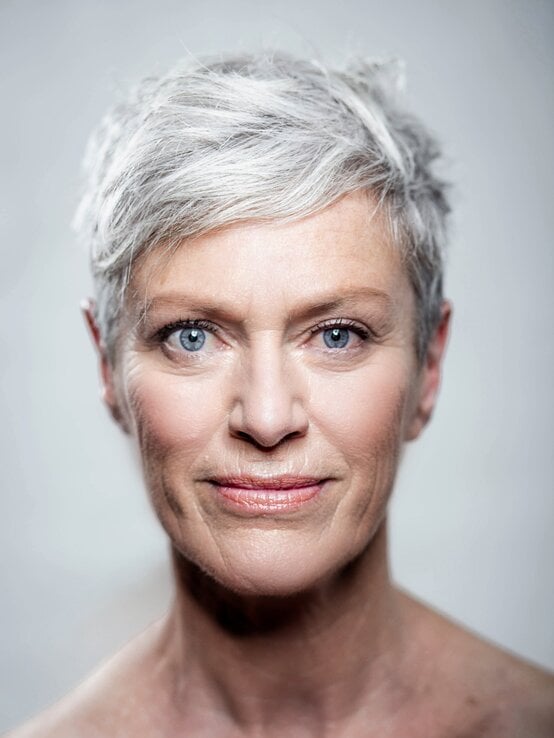 Ältere Frau mit eisgrauem Pixie-Cut und blauen Augen blickt ruhig und selbstbewusst in die Kamera  | © Westend61 / Viviane Wild via Getty Images