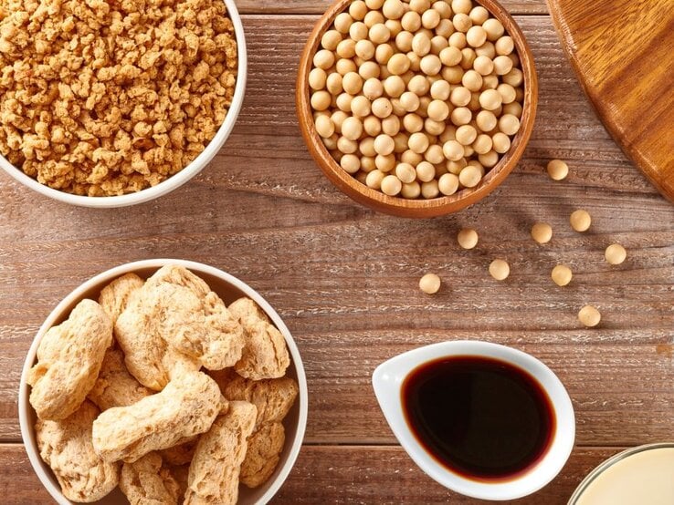 Verschiedene Sojaprodukte: Sojagranulat, Sojabohnen, Sojasauce und ein Getränk. | © Aflo Images via Canva.com