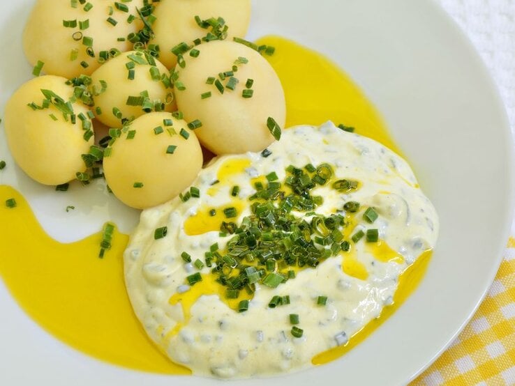 Gekochte Kartoffeln mit Quark und Leinöl, garniert mit frischem Schnittlauch auf einem weißen Teller. | © Getty Images/ drsabrinacercelovic via Canva.com