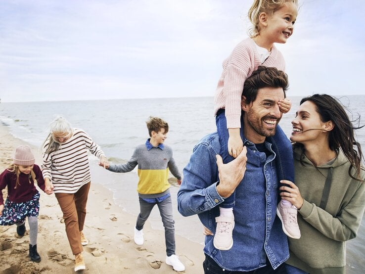 Eine glückliche Familie geht am Strand spazieren.