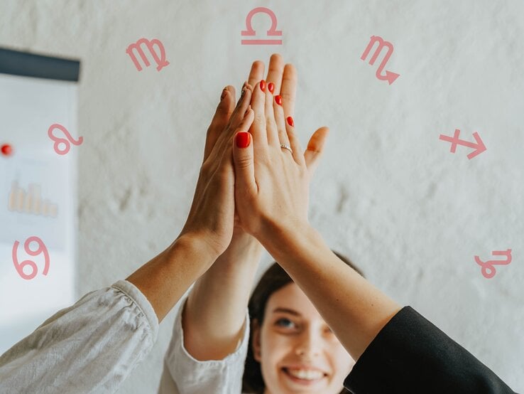 Drei Personen geben sich ein High-Five, wobei nur ihre Arme und Hände sichtbar sind. Eine Person hat rot lackierte Nägel. Im Hintergrund ist eine lächelnde Frau und eine weiße Wand mit astrologischen Symbolen der Tierkreiszeichen Löwe, Jungfrau, Waage, Skorpion, Schütze und Krebs zu sehen. Ein Diagramm ist ebenfalls teilweise sichtbar.
