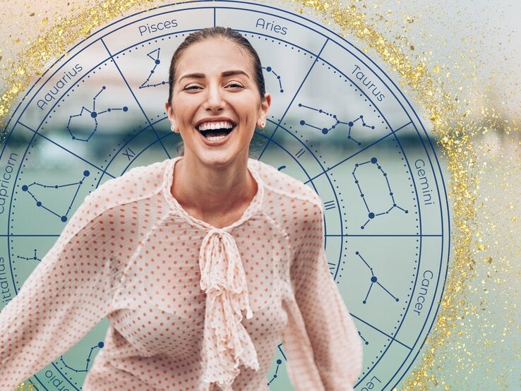 Eine lachende Frau mit zurückgebundenem Haar trägt eine gepunktete Bluse und steht vor einem astrologischen Kreis, der die Symbole und Konstellationen der zwölf Tierkreiszeichen zeigt. Der Hintergrund ist mit goldenen Glitzereffekten verziert, was die fröhliche und optimistische Stimmung des Bildes unterstreicht.