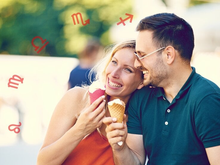 Ein lächelndes Paar genießt Eiscreme im Freien. Die Frau trägt ein orangefarbenes Oberteil und hält ein Eis mit einem rosa Waffelhörnchen, während der Mann ein grünes Poloshirt trägt und ein Eis mit einem braunen Waffelhörnchen hält. Um sie herum sind verschiedene Sternzeichen-Symbole zu sehen, darunter Löwe, Jungfrau, Waage, Skorpion und Schütze. Die Stimmung ist entspannt und fröhlich.