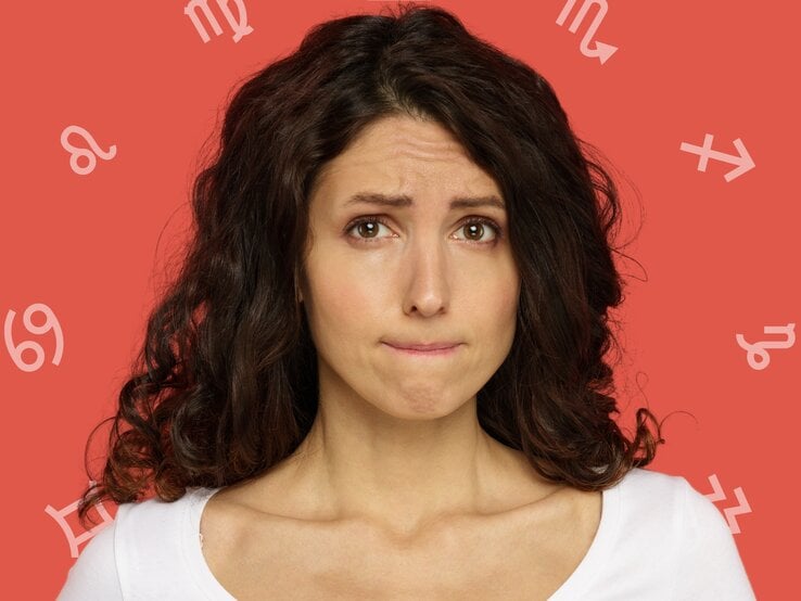 ine junge Frau mit lockigem, braunem Haar blickt besorgt und beißt leicht auf ihre Lippe. Sie trägt ein weißes Oberteil und steht vor einem roten Hintergrund, auf dem verschiedene astrologische Symbole wie Löwe, Jungfrau, Skorpion und Schütze zu sehen sind.