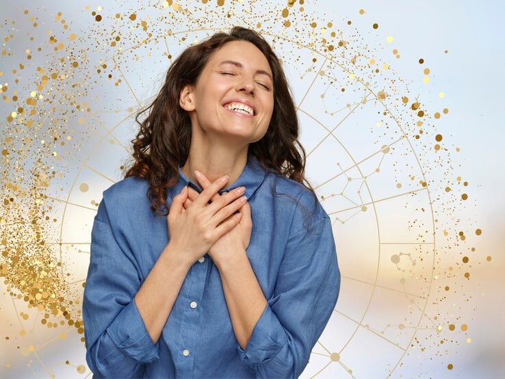 Das Bild zeigt eine junge Frau, die glücklich lächelt und ihre Hände über ihr Herz legt. Sie wirkt dankbar und voller Freude. Im Hintergrund ist ein astrologisches Rad zu sehen, umgeben von goldenen, funkelnden Punkten, die eine festliche und magische Atmosphäre schaffen. Die Frau trägt ein blaues Hemd und die gesamte Szenerie vermittelt ein Gefühl von Zufriedenheit und innerem Glück, das möglicherweise im Zusammenhang mit positiven astrologischen Einflüssen steht.