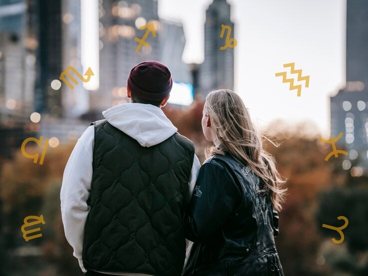 Ein Paar steht zusammen und blickt auf eine Stadtlandschaft bei Sonnenuntergang. Um sie herum sind astrologische Symbole platziert, was auf ein Liebeshoroskop oder astrologische Themen in Bezug auf Beziehungen hinweist. Die Szene wirkt ruhig und nachdenklich.