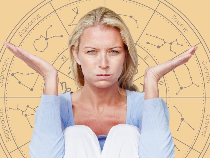 Eine blonde Frau mit ernstem und unzufriedenem Gesichtsausdruck sitzt mit angezogenen Knien und hebt beide Hände fragend oder ratlos nach oben. Sie trägt einen hellblauen Pullover. Im Hintergrund ist ein großes astrologisches Rad mit den Symbolen und Namen der Sternzeichen wie Aquarius, Taurus, Gemini und Capricorn zu sehen. Die warmen, gelblichen Farbtöne des Hintergrunds stehen im Kontrast zu ihrer angespannten Stimmung und vermitteln das Gefühl von Frustration oder Unsicherheit.