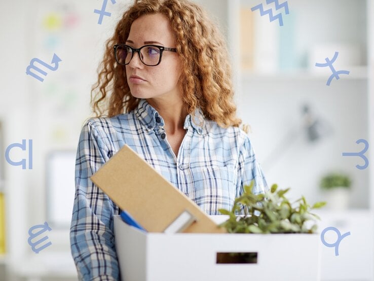 Eine junge Frau mit lockigen roten Haaren und einer Brille trägt ein kariertes Hemd und hält eine weiße Umzugskiste in den Armen. In der Kiste befinden sich ein Ordner, ein Notizbuch, eine kleine Pflanze und weitere Büroutensilien. Sie schaut nachdenklich zur Seite, ihr Gesichtsausdruck wirkt ernst und reflektierend. Der Hintergrund zeigt ein modernes Büro mit Regalen, Pflanzen und einer Schreibtischlampe. Um sie herum schweben blaue astrologische Symbole, darunter für Skorpion, Schütze, Wassermann und Fische, was eine Verbindung zur Astrologie und möglicherweise einem Jobwechsel oder beruflichen Veränderungen symbolisiert.