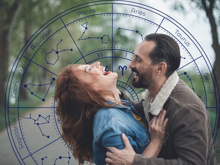 Ein lachendes Paar genießt einen romantischen Moment im Freien. Die Frau mit roten Haaren lehnt sich zurück, während der Mann sie sanft hält und beide sich strahlend ansehen. Im Hintergrund überlagert eine astrologische Tierkreisgrafik mit Sternzeichen und Konstellationen das Bild. Die Szene vermittelt Leichtigkeit, Spaß und eine verspielte, flirtende Energie, passend zum Thema Liebeshoroskop oder Flirtastrologie.