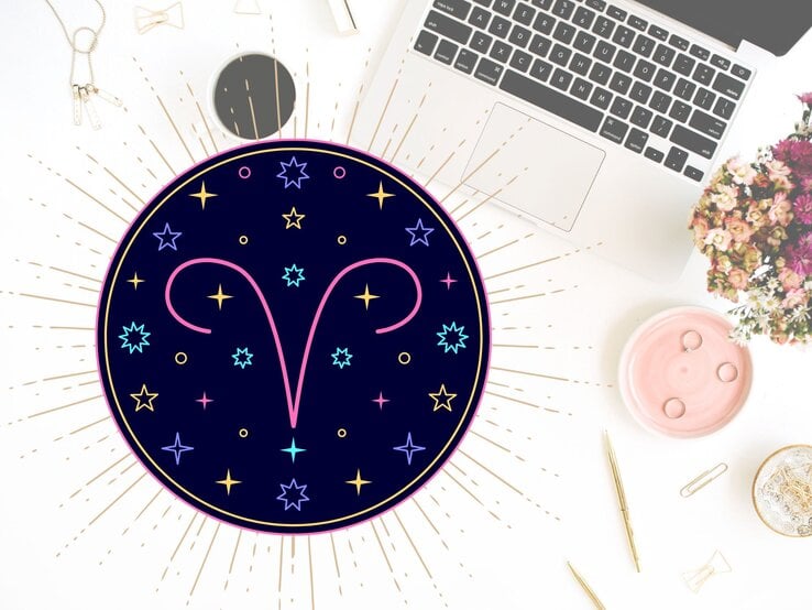 Draufblick auf einen Schreibtisch mit verschiedenen Utensilien wie goldene Kugelschreiber, Sicherheitsnadeln und der Tastatur eines Laptops. Links daneben das grafische Symbol des Sternzeichens Widder in einem dunkelblauen Kreis umgeben von gelben, pinken und hellblauen Sternen. | © Floral Deco, Julia Dreams und warmjuly via Canva.com [M]