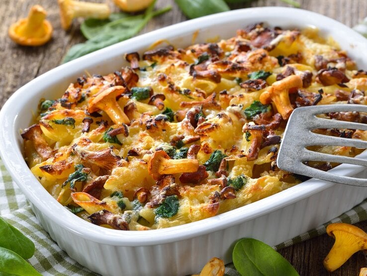 Eine Auflaufform mit dem Nudelgratin auf einem rustikalen Holztisch von schräg oben fotografiert. | © Shutterstock/ Karl Allgaeuer