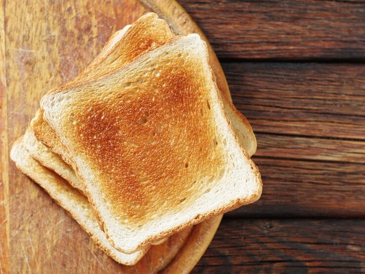 Mehrere getoastete Scheiben Toastbrot auf einem Holzbrett.  | © Shutterstock/Aleksandrs Samuilovs