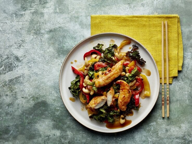 Das asiatische Gericht auf einem grünlichen Tisch mit gelber Tischdecke und Essstäbchen . Alles direkt von oben fotografiert