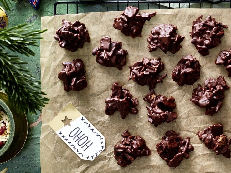Die knusprigen Süßigkeiten auf einem schwarzen Gitter mit Backpapier und dunkelgrünem Untergrund. Alles direkt von oben fotografiert.