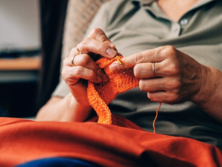 Zu sehen ist eine Frau mittleren Alters, die gerade strickt.