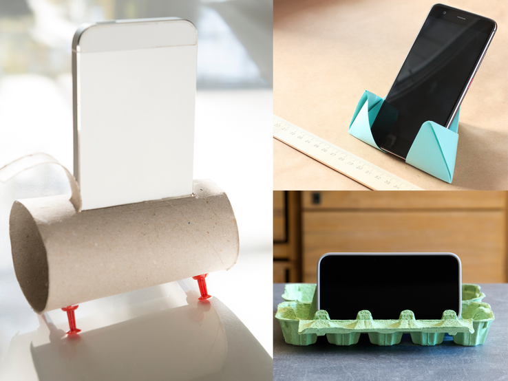 Drei Smartphones stehen in selbstgebastelten Haltern aus Toilettenrolle, Origami-Papier und grünem Eierkarton auf Tischen.