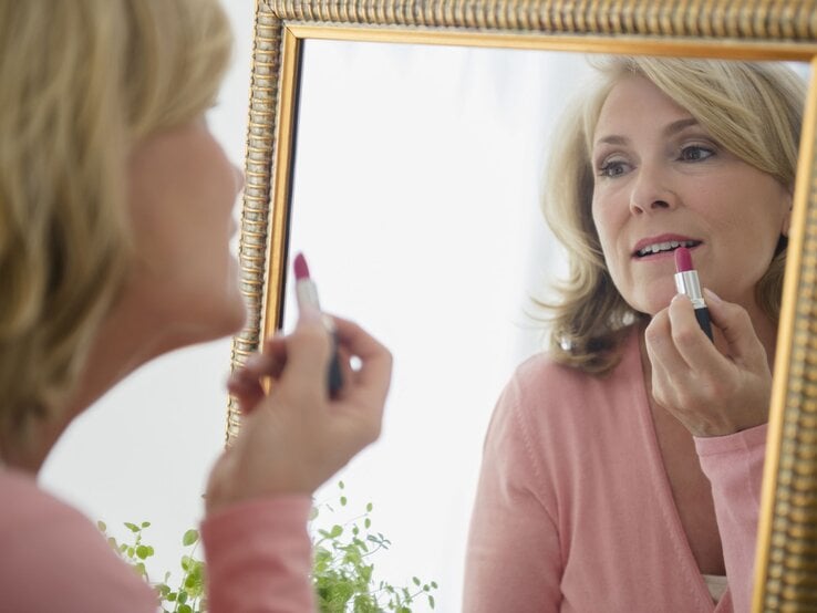 Zu sehen ist eine Frau mittleren Alters, die sich schminkt