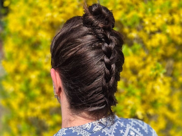 Zu sehen ist eine Frau, die die beschriebene Frisur trägt, mit braunen Haaren, vor einem Osterbusch