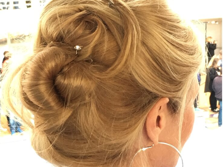 Hochgesteckte blonde Haare mit einer Haarspange mit glitzerndem Stein, kombiniert mit großen silbernen Kreolen vor heller Umgebung. | © Renate Zott 