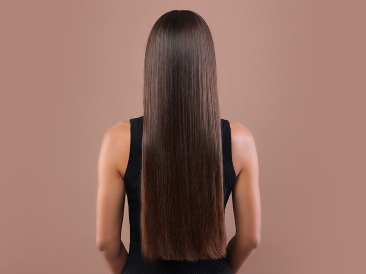 Zu sehen sind glänzende, glatte Haare vor einem beigen Hintegrund