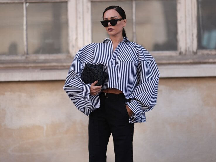 Zu sehen ist eine Frau mit braunem Pferdeschwanz, die eine blau-weiß gestreifte Bluse trägt. 