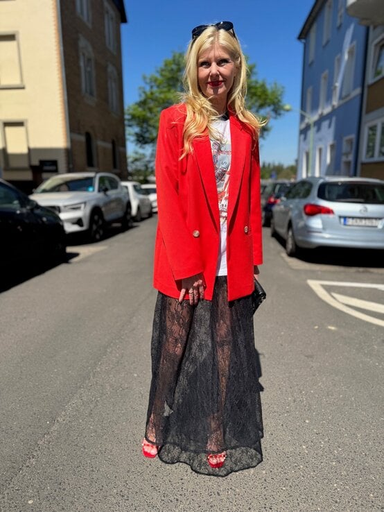 Renate Zott kombiniert auffälligen roten Blazer mit transparentem Spitzenrock und hohen roten Riemchensandalen auf Straße. | © Renate Zott
