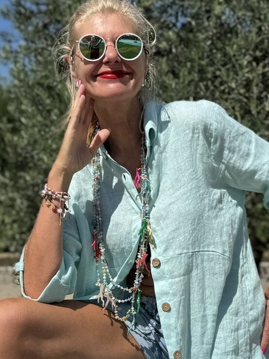 Renate Zott mit rotem Lippenstift und verspiegelter Sonnenbrille trägt türkisene Leinenbluse und bunte Statement-Ketten. | © Renate Zott 