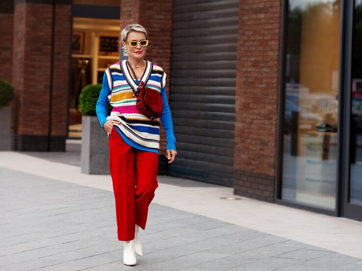 Frau in einem auffälligen bunten Outfit läuft die Straße entlang.