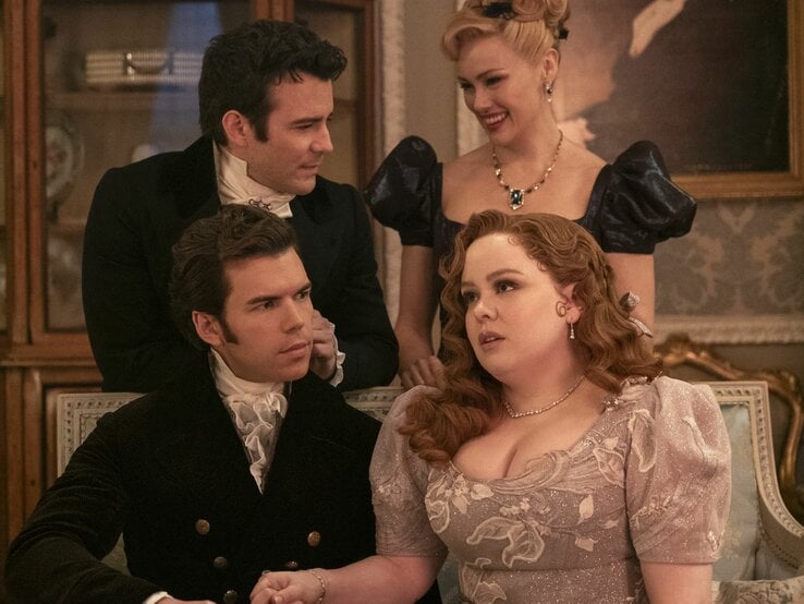 Vier elegant gekleidete Personen aus Brdigerton in historischen Kostümen, zwei Männer und zwei Frauen, unterhalten sich in einem prunkvoll dekorierten Raum.