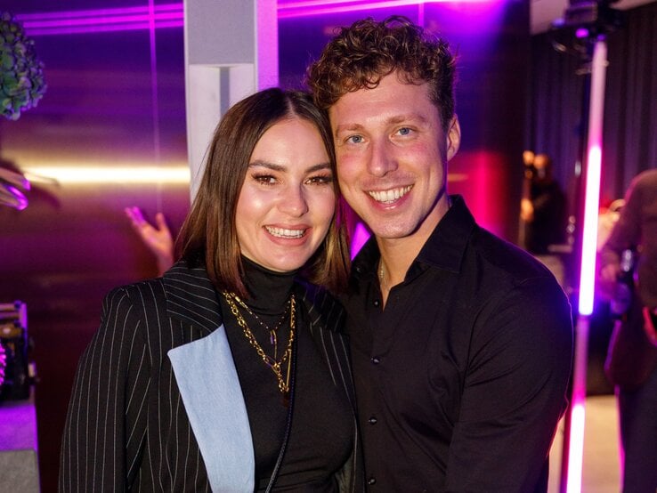 Renate Lusin und Valentin Lusin lächeln eng umschlungen in die Kamera, umgeben von pink-violettem Partylicht und stilvoller Clubatmosphäre.