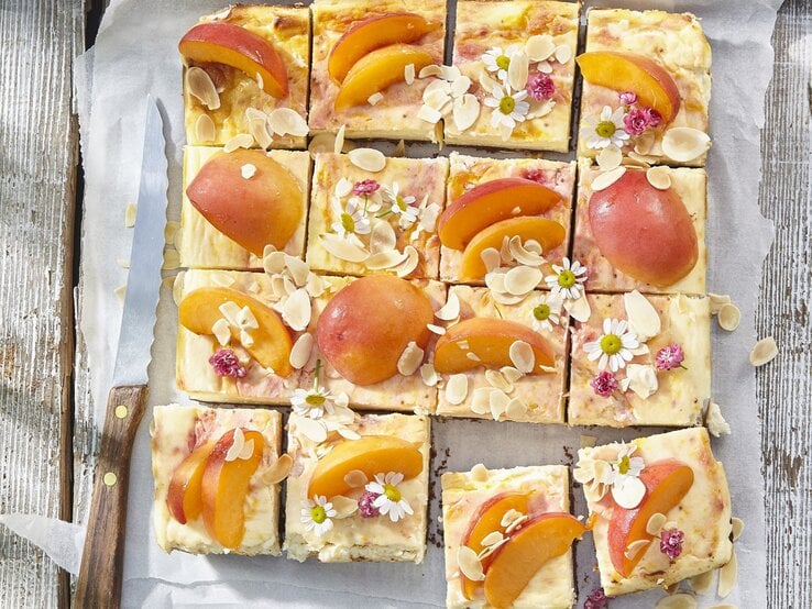 Aprikosen-Käsekuchen vom Blech auf weißem Backpapier auf hölzernem Hintergrund.  | © StockFood / Profimedia