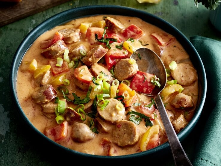Wurstgulasch mit Paprika-Frischkäse-Soße in einer Schüssel auf dunkelgrünem Hintergrund.  | © EAT CLUB/Isabell Triemer