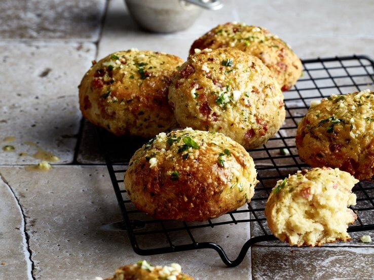 Triple-Cheese-Brötchen aus der Pfanne auf einem schwarzen Gitter auf grauem Hintergrund. 