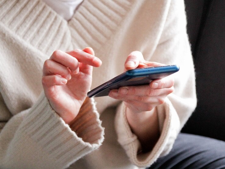 Zu sehen ist eine Frau, die ein Handy hält