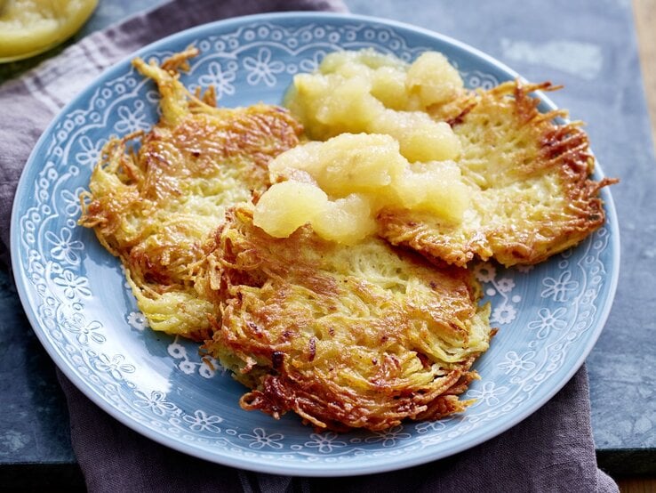 Goldbraun gebratene Kartoffelpuffer auf einem Teller mit Apfelmus.