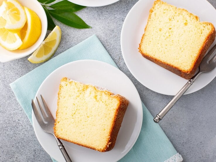 Barbarakuchen / zwei Scheiben auf kleinen, runden tellern / Kuchengabeln / Zitronenscheiben auf kleiner Schale / Draufsicht